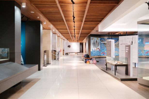 Corredor iluminado de uma exposição de design moderno, com ambientes expositivos e passarelas vazias.